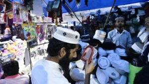 A devotee checks his scull cap before buying it from the market at shrine of Sufi saint Hazrat Khwaja Syed Nizamuddin Auliya