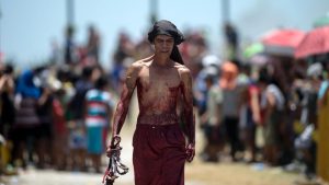 A flagellant walks in front of crosses before a re-enactment of the Crucifixion of Christ. Catholics do not eat meat on Good Friday but can eat fish instead and it is also customary to eat warm hot cross buns