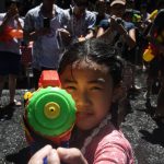 A girl aims a water pistol at the camera during Songkran, Thailand's traditional New Year festival, on Silom road in Bangkok