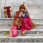 A girl dressed as Kumari, sipping a soft drink as she sits on stairs after attending rituals to celebrate the Navratri Festival inside the Adyapeath Temple, on the outskirts of Kolkata