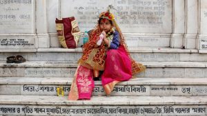 A girl dressed as Kumari, sipping a soft drink as she sits on stairs after attending rituals to celebrate the Navratri Festival inside the Adyapeath Temple, on the outskirts of Kolkata