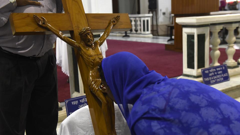 A lady kisses the Holy Cross during the Good Friday mass gathering at Sacred Heart Cathedral in New Delhi