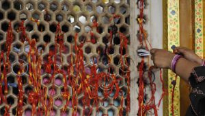 A lady ties sacred thread at a lattice door at the shrine to observe ‘mannat’ or a prayer of belief