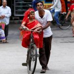 A man carries his daughter, dressed as Kumari, on a bicycle, as they arrive to attend rituals to celebrate the Navratri Festival, inside the Adyapeath Temple, on the outskirts of Kolkata, April 5, 2017