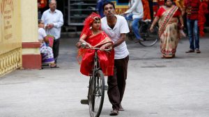 A man carries his daughter, dressed as Kumari, on a bicycle, as they arrive to attend rituals to celebrate the Navratri Festival, inside the Adyapeath Temple, on the outskirts of Kolkata, April 5, 2017