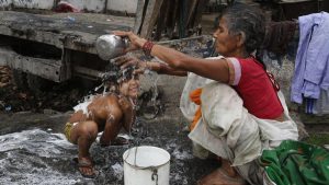 A woman bathes her child near the polluted water on Earth Day in Allahabad.