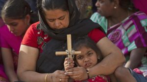 An Indian mother and daughter pray as they watch the re-enacting of the crucifixion of Jesus Christ during Good Friday in Hyderabad, India