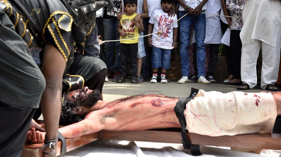 Children watching as artist enacts the crucifixion of Jesus on the occasion of Good Friday at Our Lady Lourdes Church at Cambridge Layout in Bengaluru