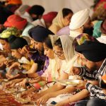 Sikh devotees eat a community vegetarian meal, known as 'langar' at a Gurdwara on Baisakhi, in Noida