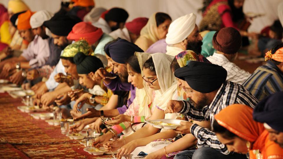 Sikh devotees eat a community vegetarian meal, known as 'langar' at a Gurdwara on Baisakhi, in Noida