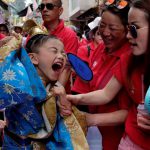 A boy in traditional Chinese costume reacts to heat during the Bun Festival parade.
