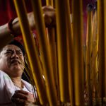 A devotee places his joss stick in an urn at a temple during the annual Cheung Chau bun festival.