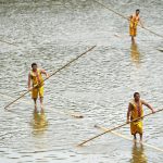 Participants paddle on bamboo poles during the Dragon Boat festival