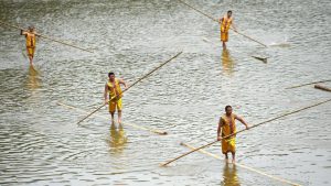 Participants paddle on bamboo poles during the Dragon Boat festival