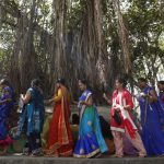 Women in groups move together to offer prayers to the banyan tree. Ganga water is poured and threads of red or yellow colour are tied around the tree chanting prayers.