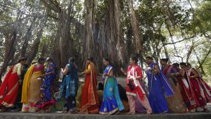 Women in groups move together to offer prayers to the banyan tree. Ganga water is poured and threads of red or yellow colour are tied around the tree chanting prayers.