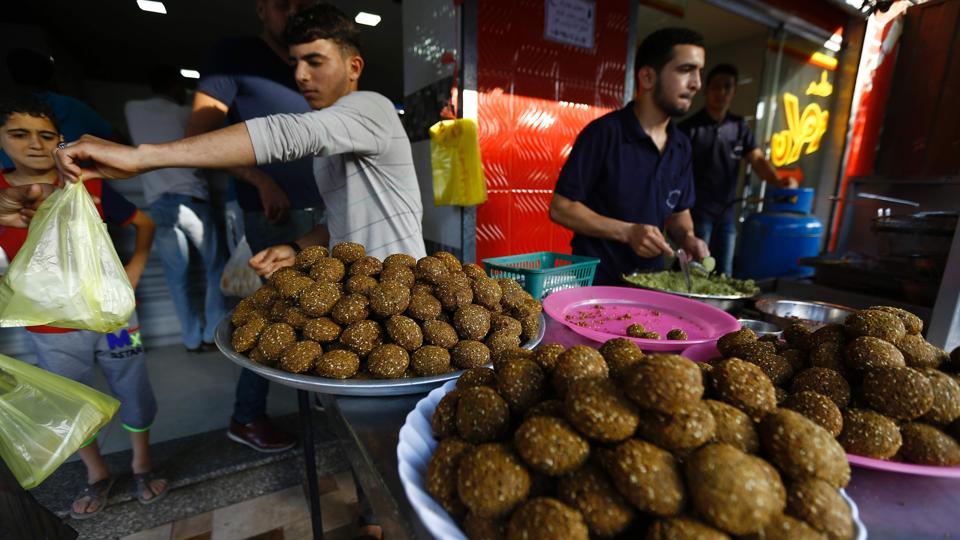 A Palestinian street vendor sells falafel at his stall during Ramadan in Gaza City. Savoury snacks are popular choices for breaking the fast at sunset throughout the Middle-East.