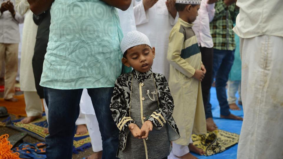 A boy rests on his father as he attends the morning prayers outside the Bandra railway station in Mumbai