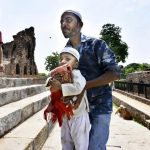 A man helps a child carrying a prayer mat up the steps of the Firoz Shah Kotla mosque on June 23, 2017 in New Delhi