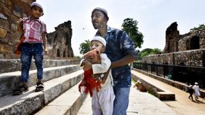 A man helps a child carrying a prayer mat up the steps of the Firoz Shah Kotla mosque on June 23, 2017 in New Delhi