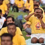 A man speaks on the phone while occupied with a yoga pose on an International Day of Yoga session at Kanteerava Stadium in Bengaluru, Karnataka