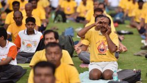 A man speaks on the phone while occupied with a yoga pose on an International Day of Yoga session at Kanteerava Stadium in Bengaluru, Karnataka