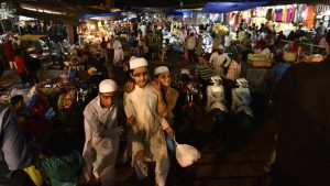 A young trio carries their shopping out from a market coming alive with Eid around the corner