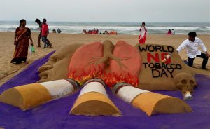 Sand artist Manas Sahoo creates a sand sculpture on eve of 'World No Tobacco Day', in Puri, on Tuesday.