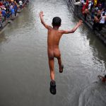A boy jumps into the Bagmati River flowing through the premises of Pashupatinath temple during the sacred thread festival at the Pashupatinath temple in Kathmandu, Nepal.