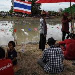 Spectators sit under umbrellas next to a rice paddy field being used for buffalo racing during the annual rice planting festival.