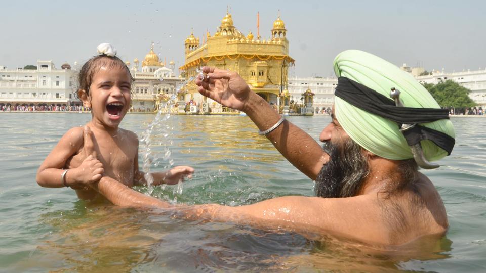 A devotee and his child take a dip in the holy sarovar (water tank). Guru Ram Das was fourth of the ten Sikh gurus.