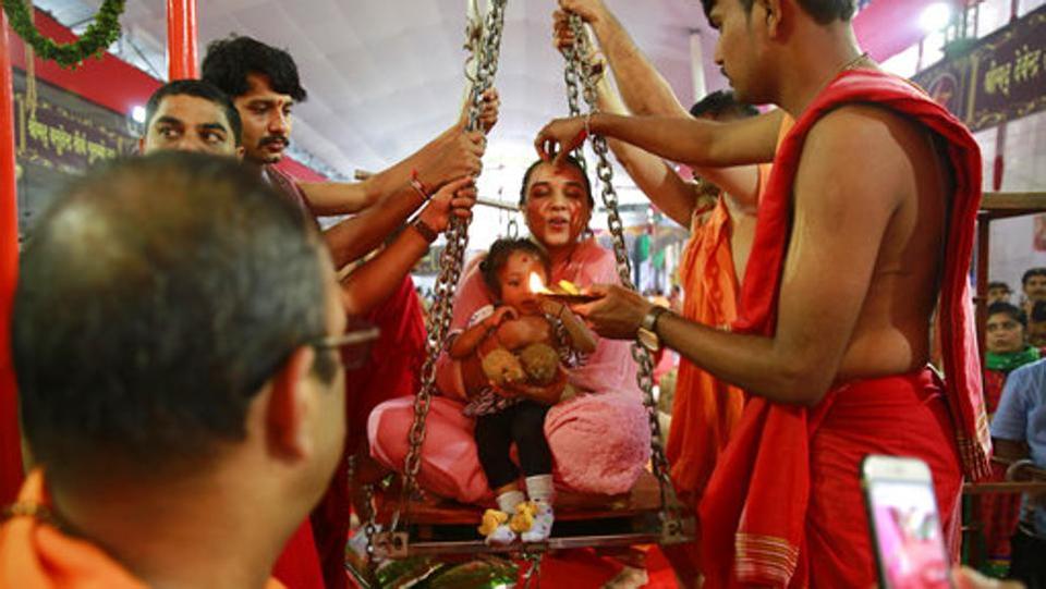 A woman and her child are weighed on a weighing scale to donate their equivalent weight in food items during Ganesh Chaturthi festival celebrations in Mumbai. Ganesh Chaturthi is believed to mark the birth anniversary of the deity and is celebrated on the fourth day (chaturthi) of the Hindu calendar month of Bhadrapada.