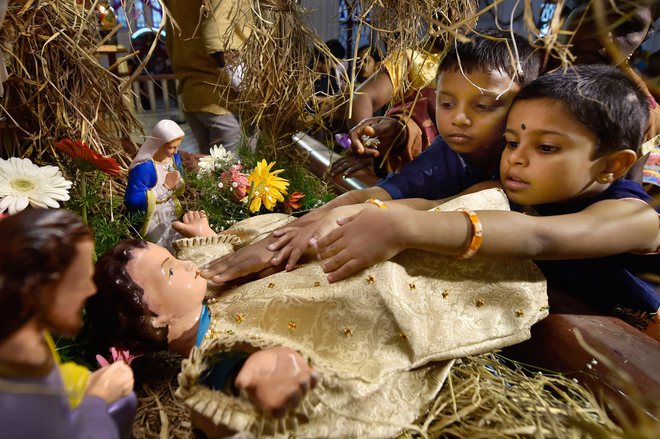Children touching the statue of baby Jesus to express their love after attending a mass prayer at the Santhome Church on the occasion of Christmas festival in Chennai on December 25, 2017