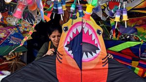 A young woman checks out a huge kite shaped like a ferocious shark in Bandra.