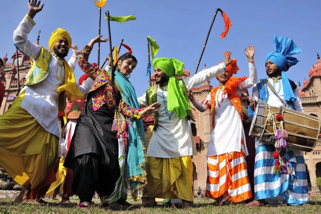 College students, wearing traditional Punjabi dresses, dance during the Lohri festival celebrations in Amritsar on January 12, 2018.