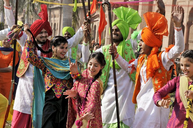 College students, wearing traditional Punjabi dresses, dance during the Lohri festival celebrations in Amritsar on January 12, 2018.