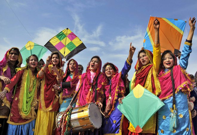 Women, dressed in their traditional Punjabi attire, fly kites as they celebrate the festival of Lohri in Amritsar on January 12, 2018.