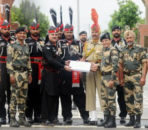 Pakistani Wing Commander Bilal (4L) presents sweets to Indian Border Security Force (BSF) Commandant Sudeep (2R) during a ceremony to celebrate Pakistan's Independence Day at the India-Pakistan Wagah border post at Attari