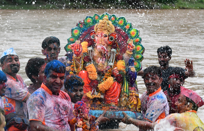 Devotees spray water on a statue of Lord Ganesha during immersion ceremony at Ghaggar River in Panchkula, Haryana