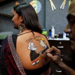 An artist applies final touches to a body paint tattoo sketched on the back of a woman in preparations for the upcoming Navratri in Ahmedabad on September 24, 2019.