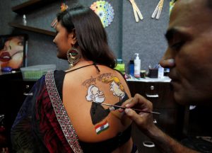 An artist applies final touches to a body paint tattoo sketched on the back of a woman in preparations for the upcoming Navratri in Ahmedabad on September 24, 2019.