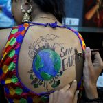 An artist applies final touches to a body paint tattoo sketched on the back of a woman in preparations for the upcoming Navratri in Ahmedabad on September 24, 2019.
