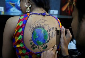 An artist applies final touches to a body paint tattoo sketched on the back of a woman in preparations for the upcoming Navratri in Ahmedabad on September 24, 2019.