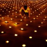 A person lights a candle as 330,000 of them are arranged in the shape of the earth to set a Guinness World Record during Earth Day, Thailand