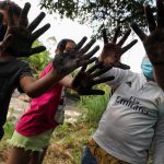 Activists show their muddy hands after planting trees to mark Earth Day, in Villeta, Colombia