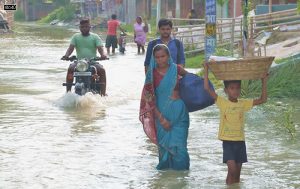 People wade through a flooded street following incessant monsoon rainfall, at Shekhpur Dhab in Bihar’s Muzaffarpur district on July 5, 2021