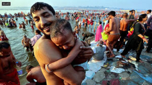 Devotee holds a child as they leave after taking a dip at Sangam