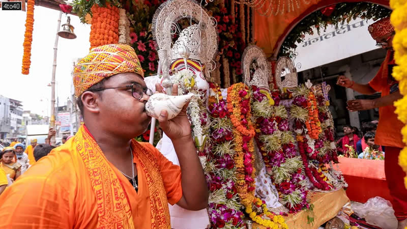 A priest blows a conch as the idols of Lord Jagannath
